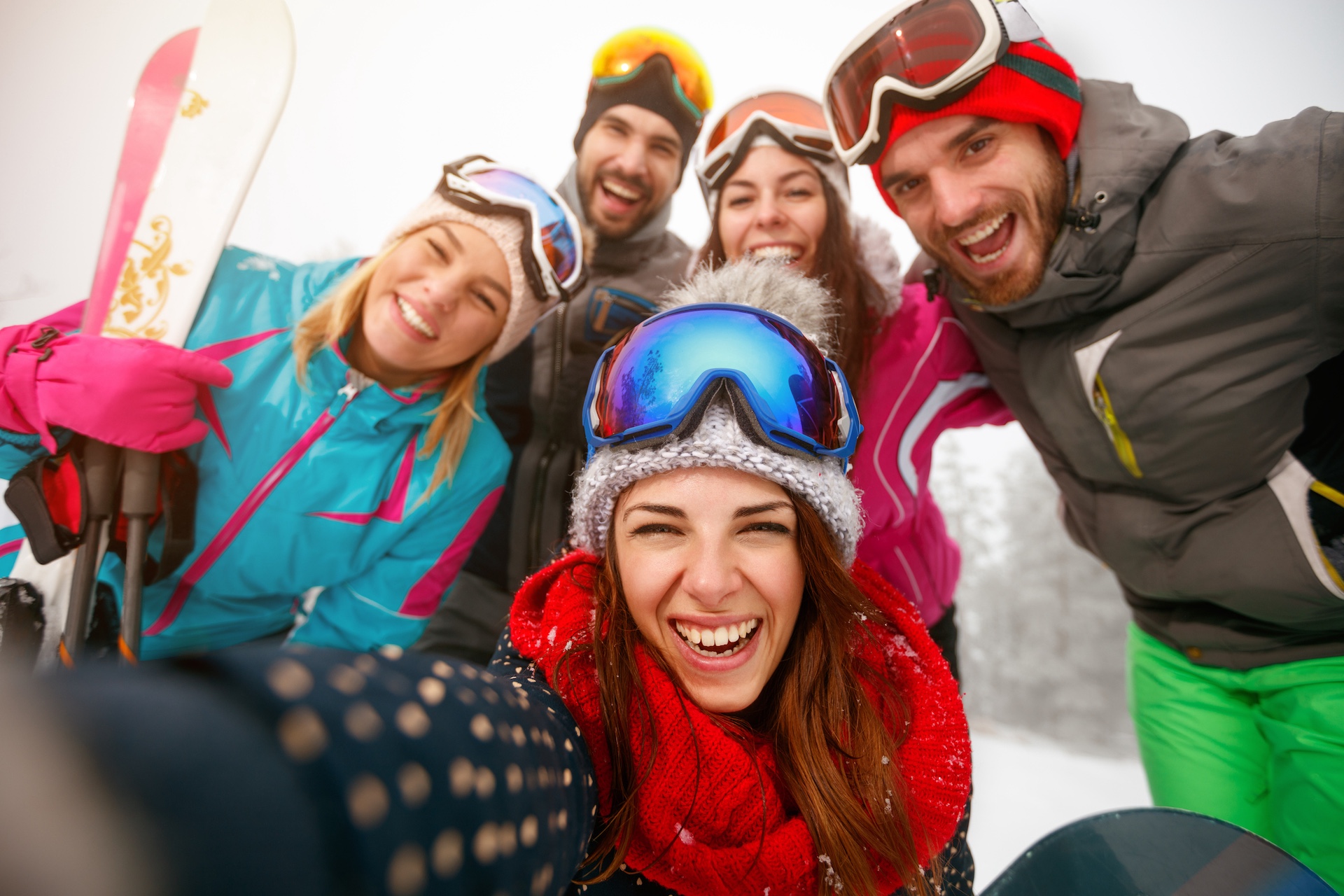 Gruppe von fünf Personen in Skibekleidung mit Skibrillen und Handschuhen, die in die Kamera lächeln.