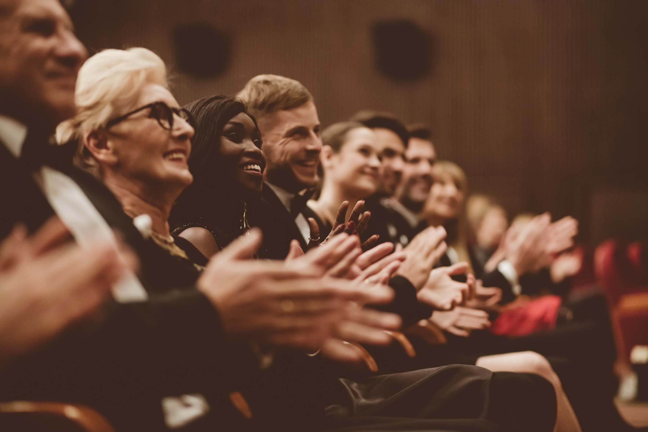 Publikum in einem Theater oder Konzertsaal klatscht applaudierend in die Hände.