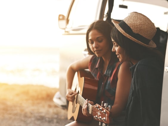 Two women sit by a van
