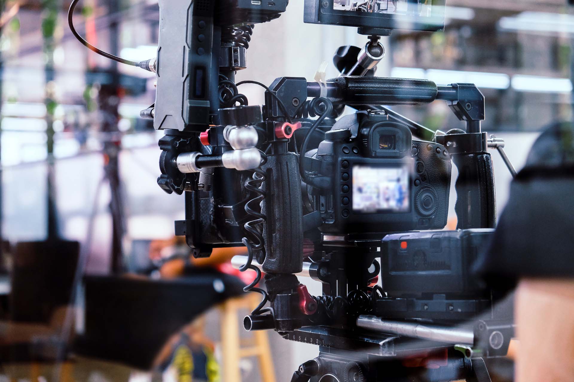 Close-up of a professional video camera setup on a tripod with a blurred background of a studio environment.