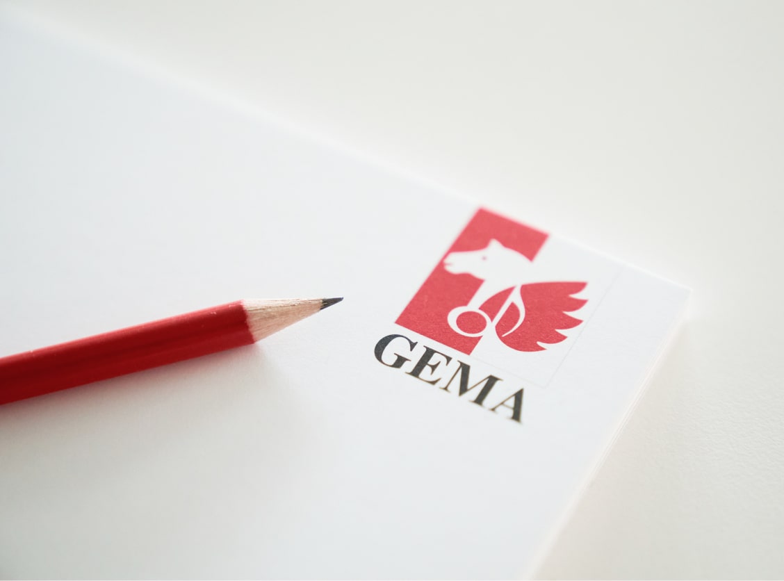 A red pencil on white paper with a red and white logo featuring a winged horse and the text