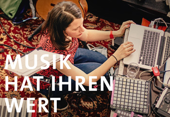Woman using a laptop on a patterned rug, surrounded by music equipment. Text reads