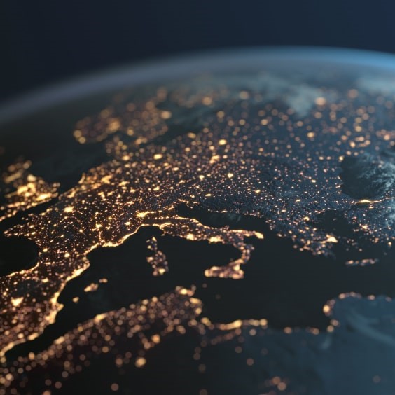 A view of Earth from space at night, showing city lights glowing across Europe and surrounding regions.
