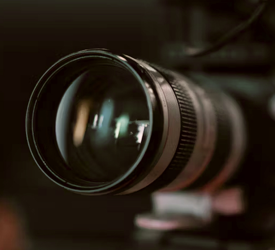 Close-up of a camera lens with reflections, set against a dark background.