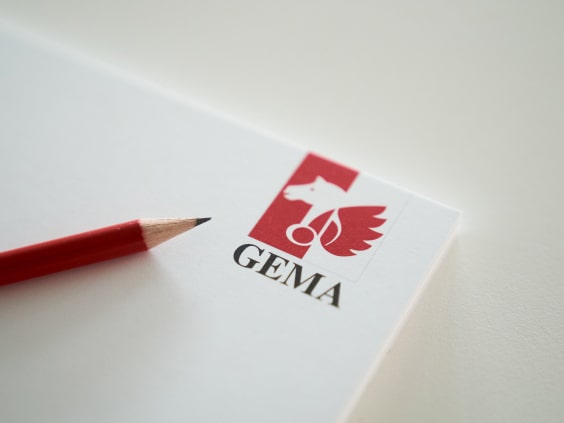 A red pencil on white paper with a red and white logo featuring a horse and wings, labeled 
