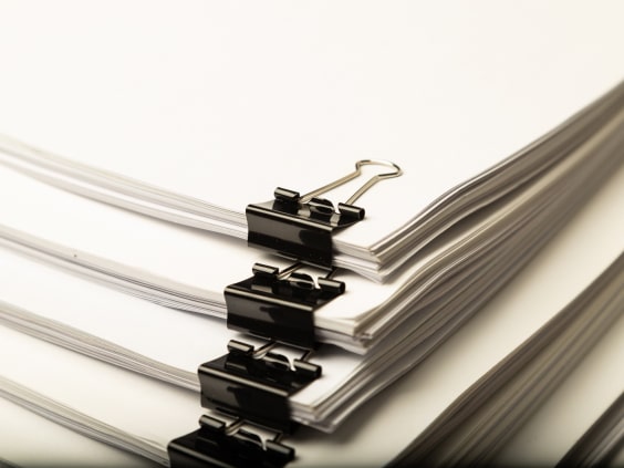 Stacks of white paper secured with black binder clips.